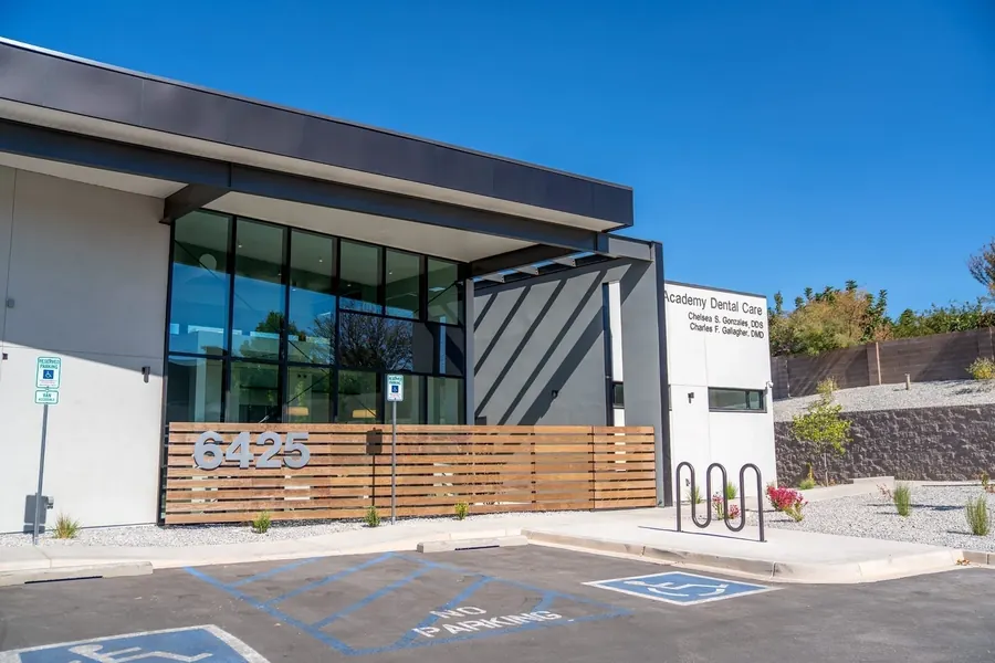 The front of the Academy Dental Care building, with the 6425 house number on the timber slats and parking outside.