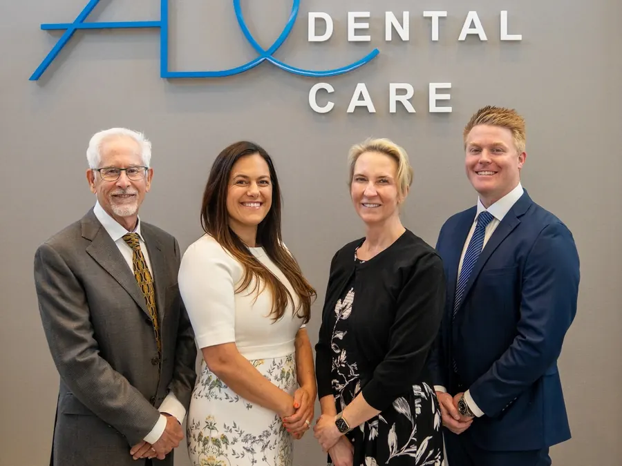 Drs. Gallagher, Gonzales, VanLeeuwen and Krohnfeldt standing in front of the Academy Dental Care logo sign.
